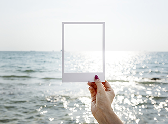 picture of a hand holding a frame towards the ocean